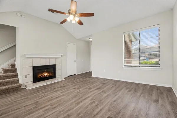 a view of an empty room with wooden floor fireplace and a window