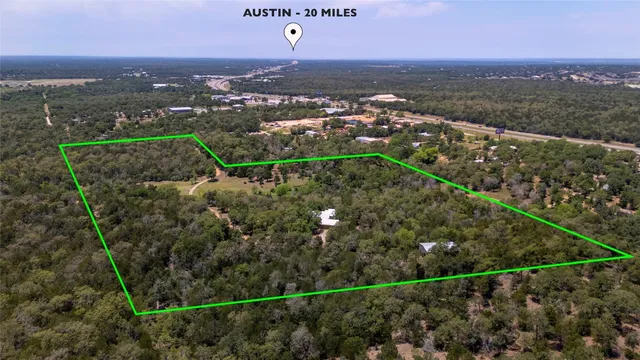 an aerial view of a residential houses with outdoor space and trees