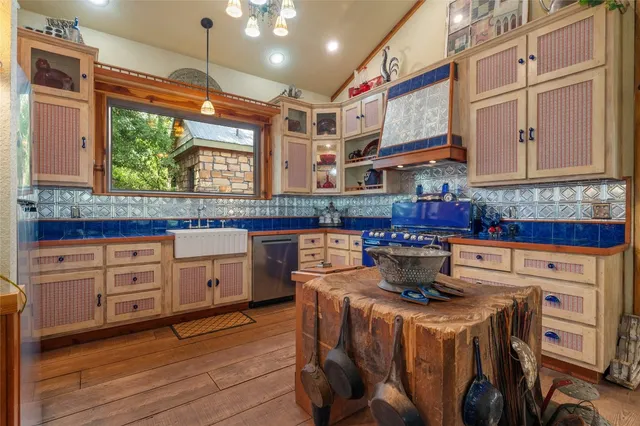 a kitchen with stainless steel appliances granite countertop a stove a sink dishwasher and white cabinets with wooden floor