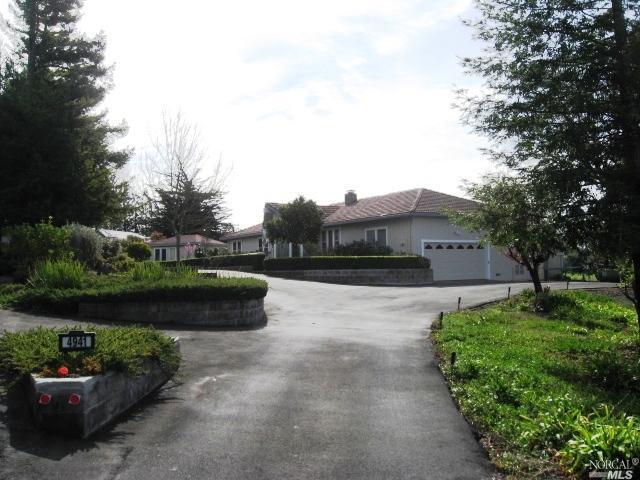 a view of a garden with a bench and some cars