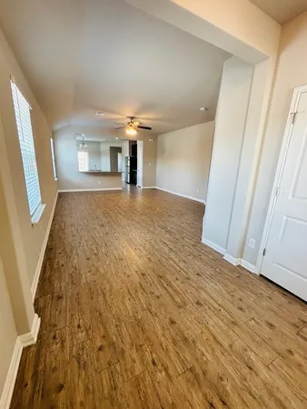 a view of empty room with wooden floor and fan