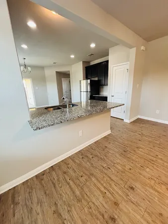 a view of kitchen with kitchen island granite countertop a sink and refrigerator