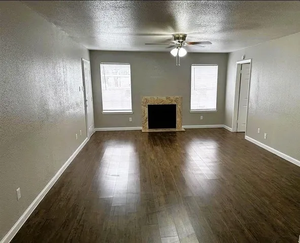 an empty room with wooden floor a fireplace and windows