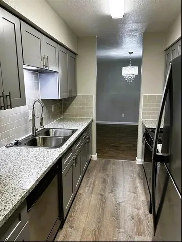 a kitchen with granite countertop a sink a stove and cabinets