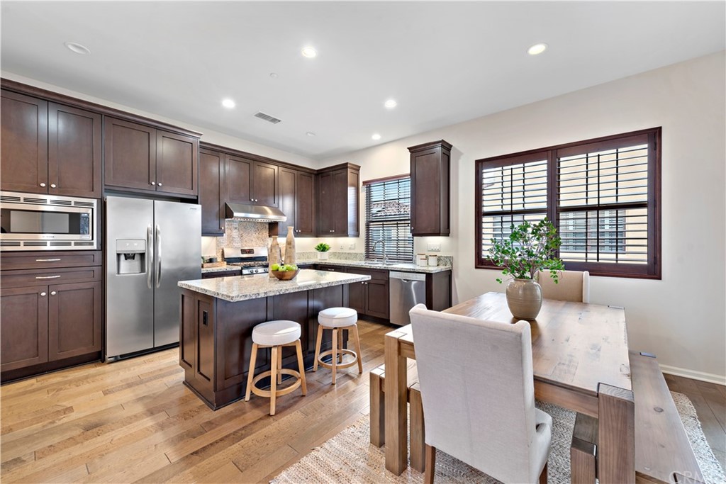 113 Painted Trellis Irvine, CA 92620 - Photo 6 of 26 a kitchen with a refrigerator a counter space dining table and chairs