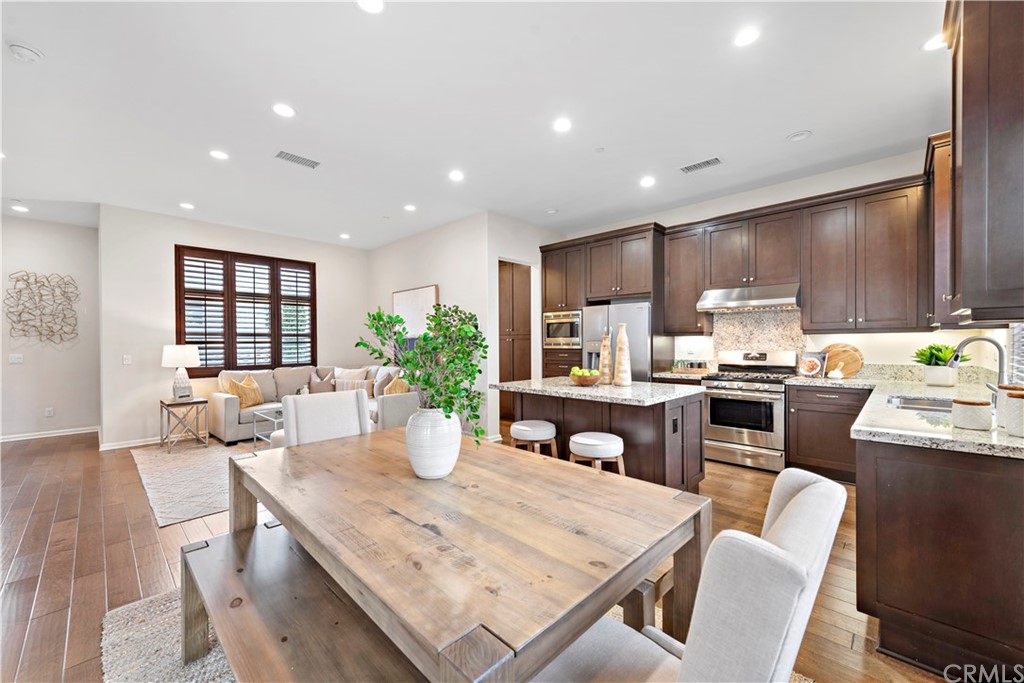 113 Painted Trellis Irvine, CA 92620 - Photo 9 of 26 a dining room with kitchen island furniture a chandelier wooden floor and kitchen view