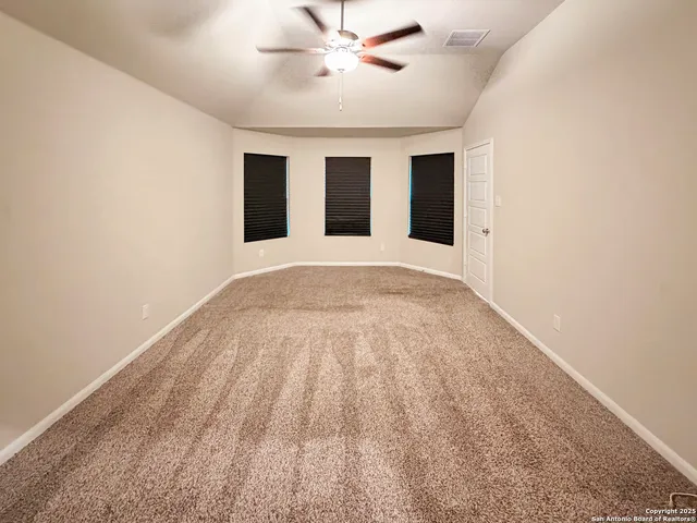 an empty room with windows and fan