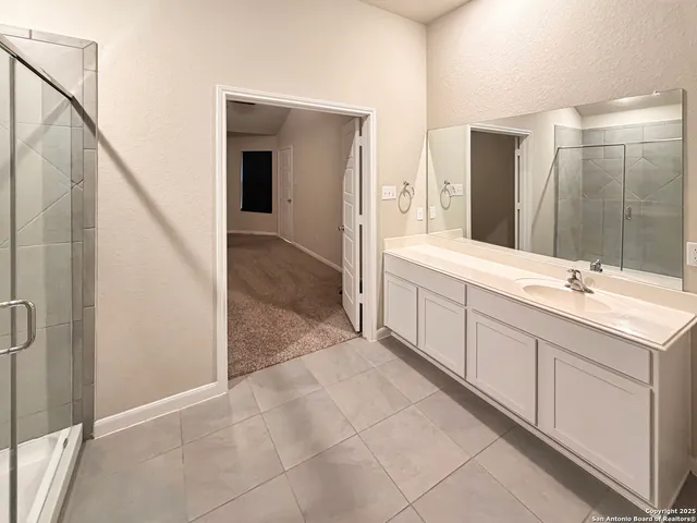 a spacious bathroom with a double vanity sink a mirror and a shower