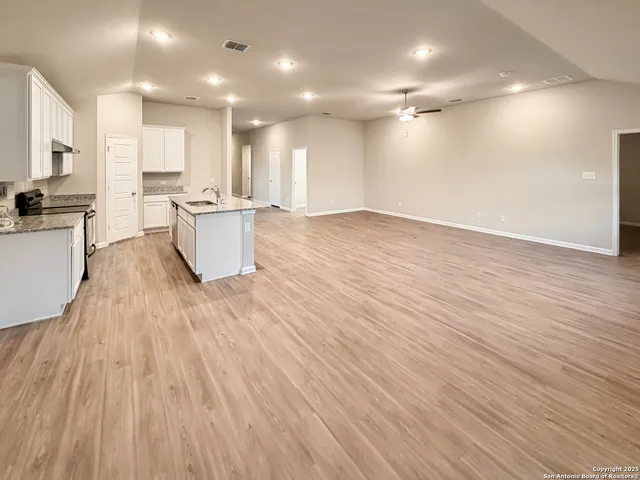 a view of kitchen with kitchen island wooden floors and stainless steel appliances