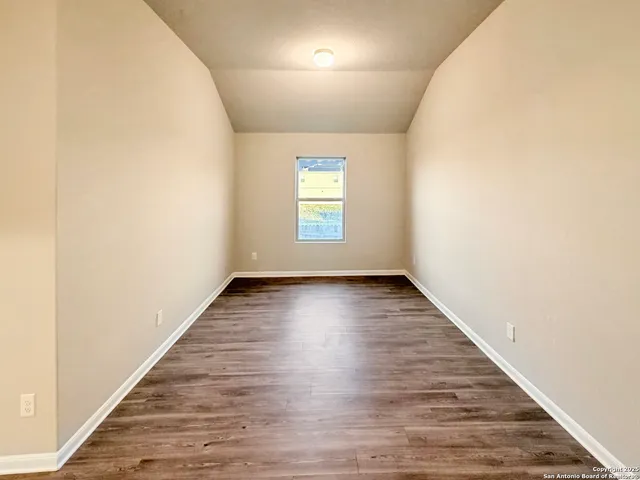 an empty room with wooden floor and window