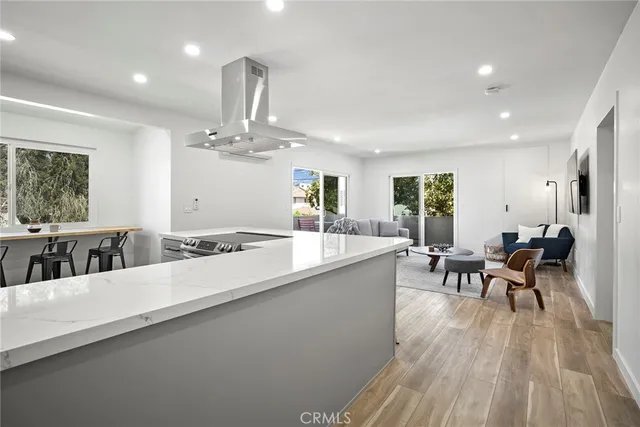 a large kitchen with stainless steel appliances a dining table chairs and a large window