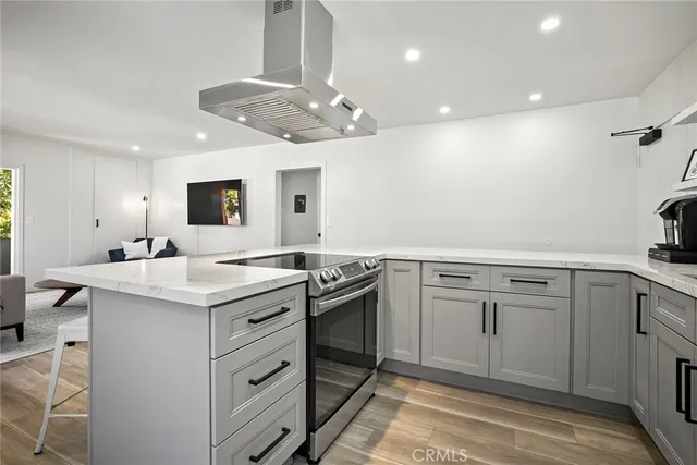a kitchen with a sink dishwasher a stove and white cabinets with wooden floor