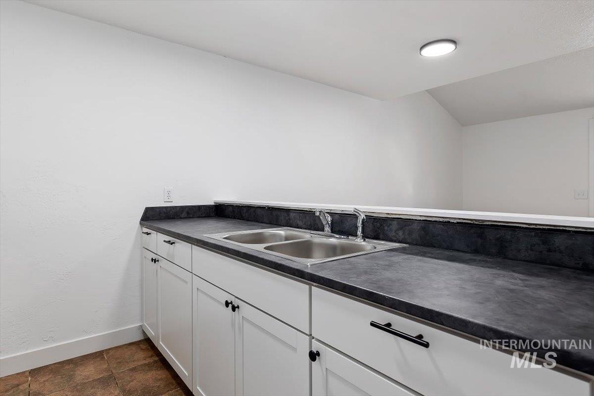 259 Pheasant Road, Unit 84 Twin Falls, ID 83301 - Photo 8 of 25 White shaker-style cabinetry with black hardware, complementing the dark countertop featuring a dual basin sink with chrome fixtures