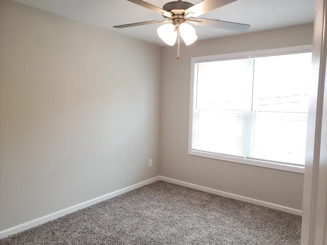 an empty room with a window and a fan