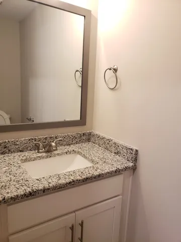 a bathroom with a granite countertop sink and mirror