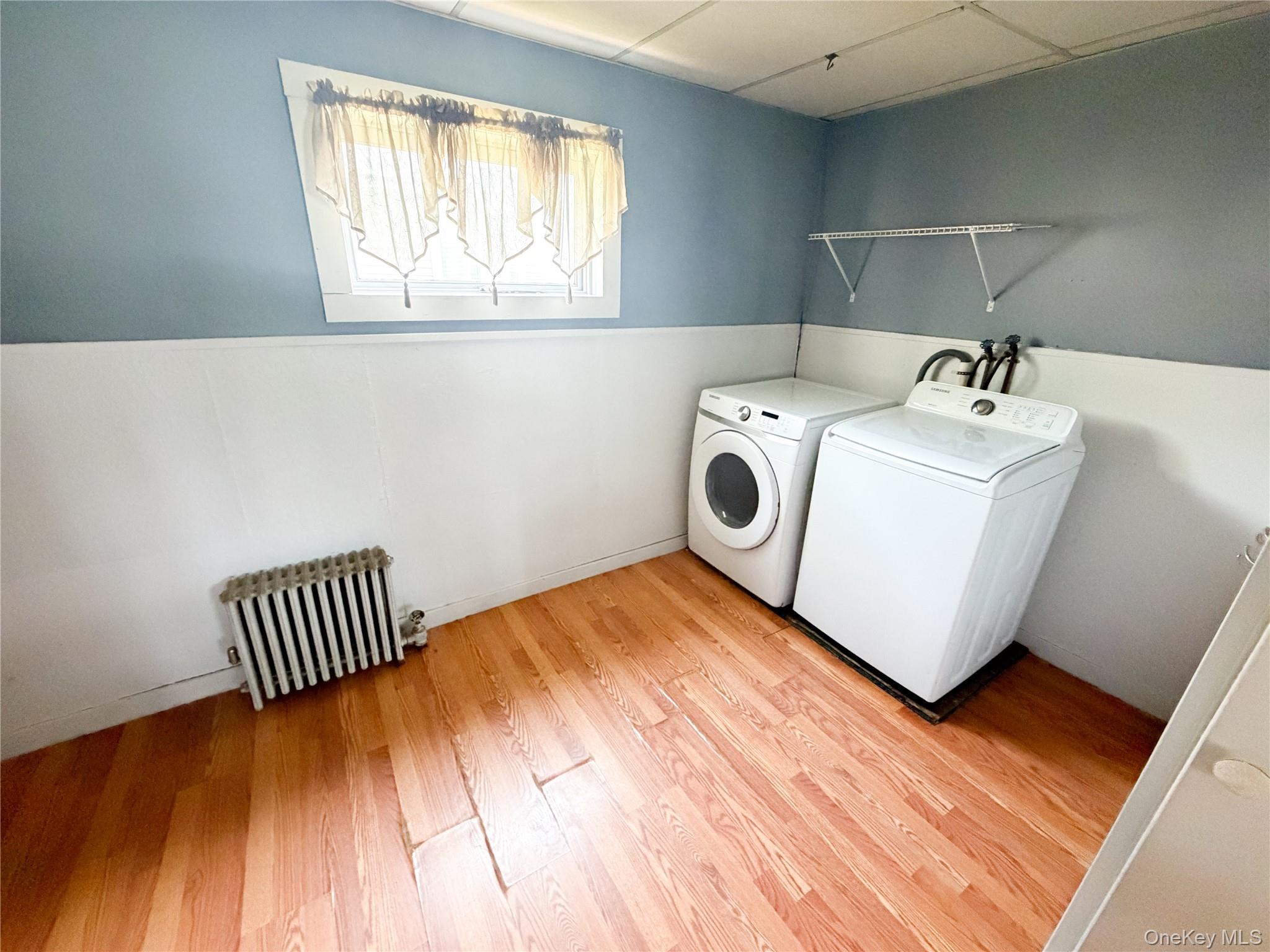 77 Rockland Road Roscoe, NY 12776 - Photo 12 of 20 Dedicated laundry area featuring wood-finish flooring, a white baseboard, light blue walls, and an included radiator