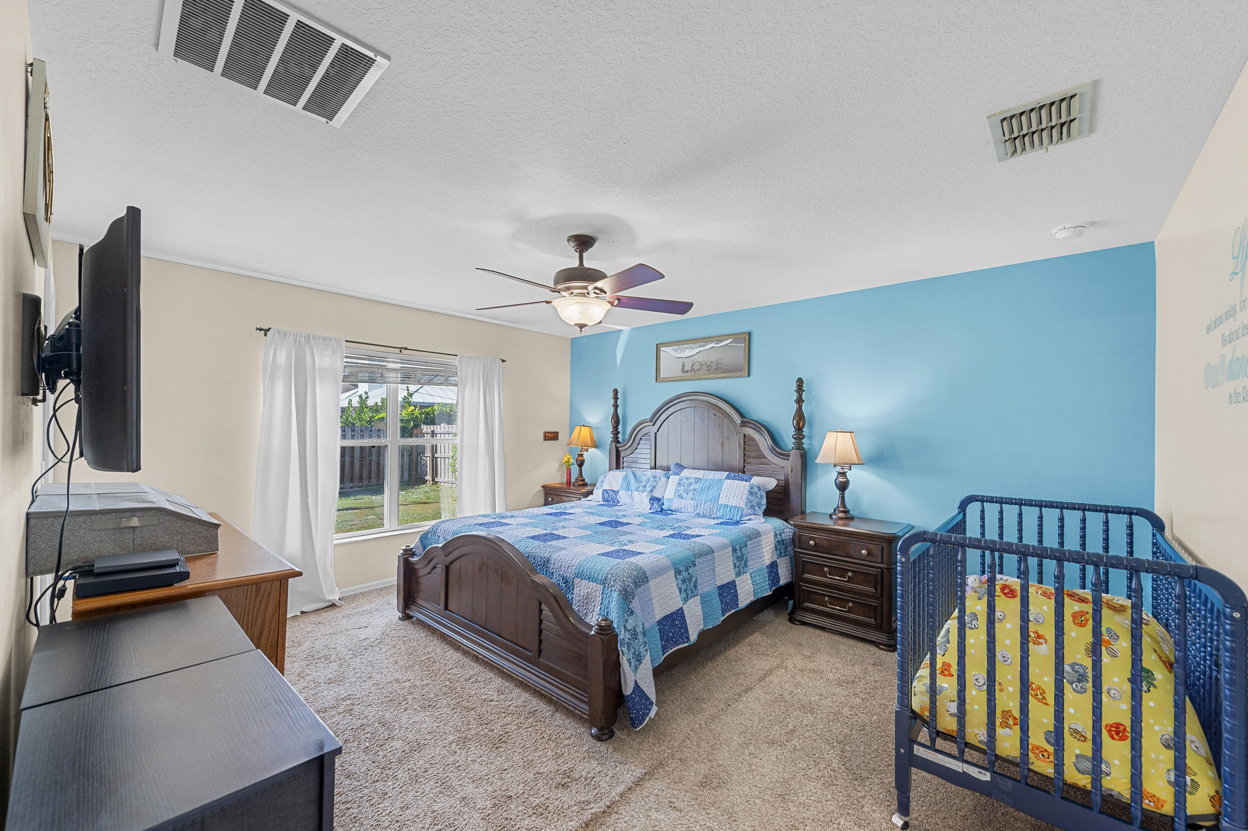 4164 Southwest Spickler Street Port St. Lucie, FL 34953 - Photo 16 of 35 a bedroom with a bed and a chandelier