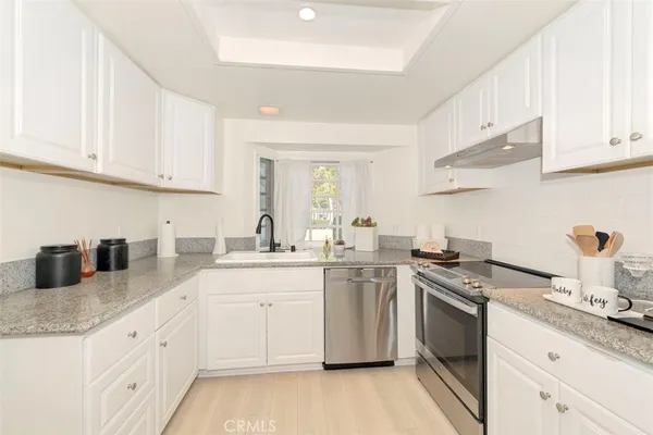 a kitchen with granite countertop white cabinets sink and stainless steel appliances