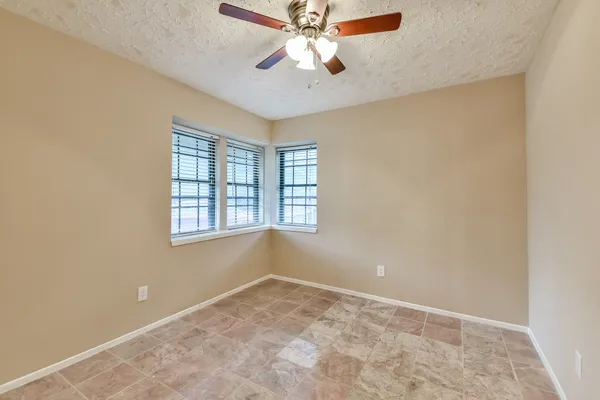 an empty room with windows and fan