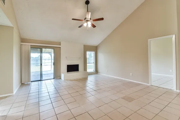 a view of an empty room with window and chandelier fan