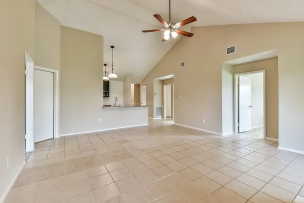 a view of a livingroom with a chandelier fan and kitchen view