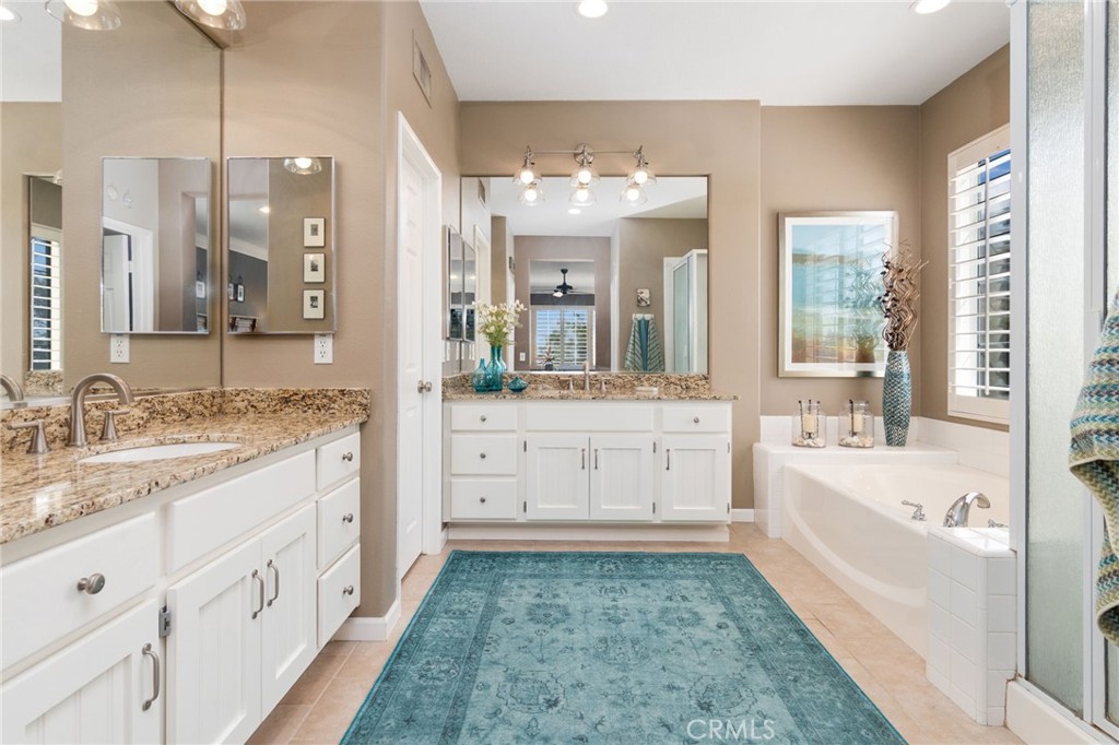 13939 Guidera Drive Rancho Cucamonga, CA 91739 - Photo 25 of 46 a bathroom with a double vanity sink a mirror a bathtub and next to a window