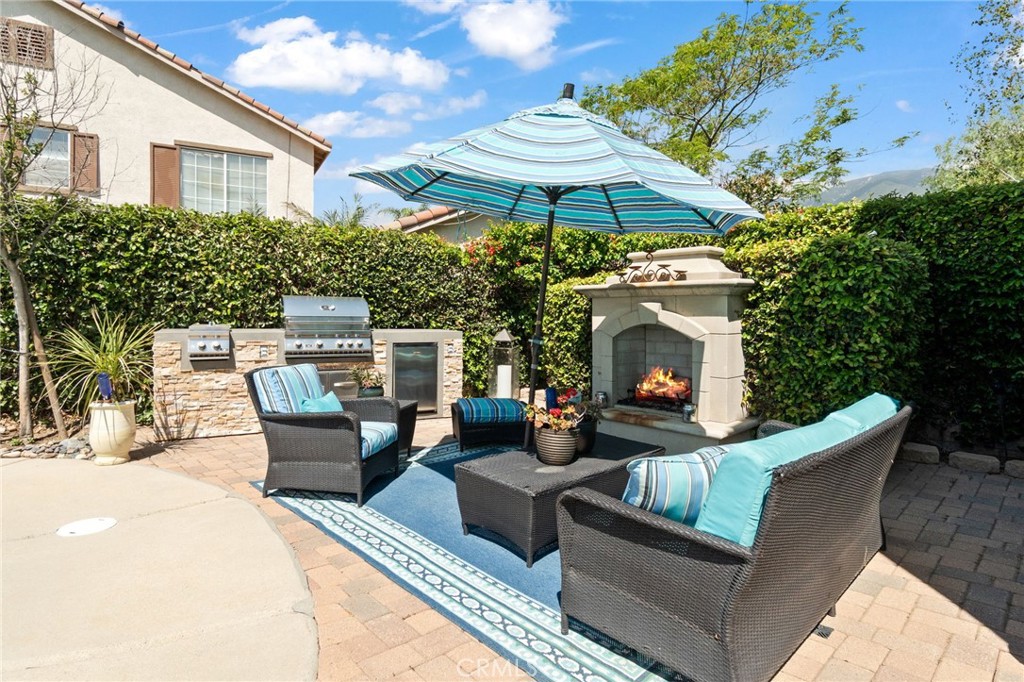 13939 Guidera Drive Rancho Cucamonga, CA 91739 - Photo 44 of 46 a view of a patio with couches table and chairs under an umbrella with a fireplace