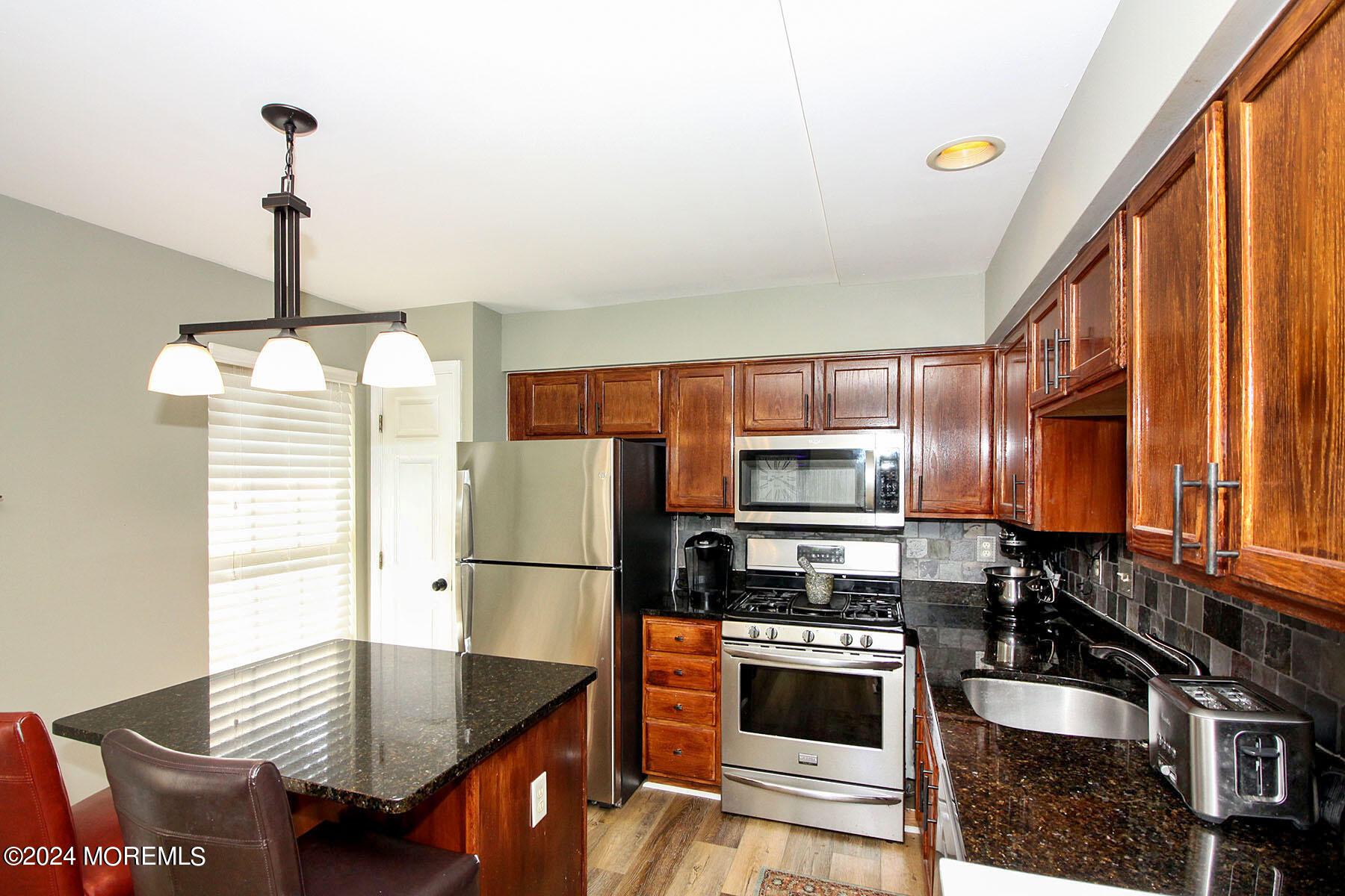 19 Saxton Road, Unit 58 Farmingdale, NJ 07727 - Photo 6 of 31 a kitchen with granite countertop a refrigerator a stove and a sink with wooden floor