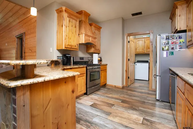 a kitchen with stainless steel appliances granite countertop wooden cabinets a sink and dishwasher with wooden floor