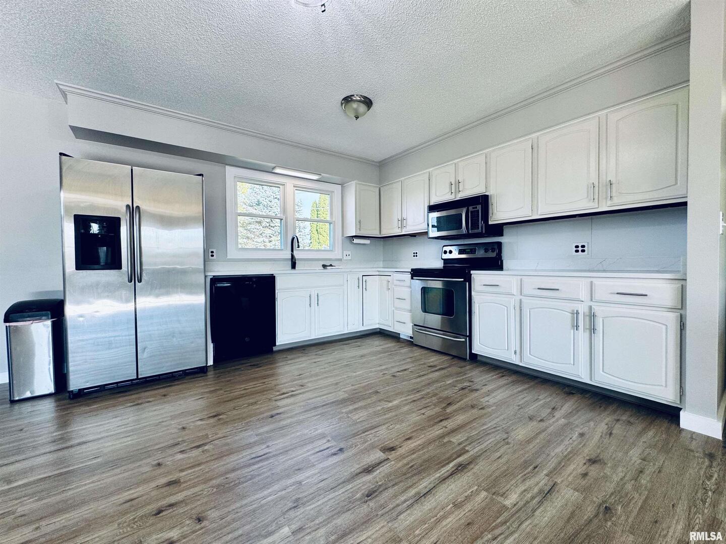 708 Tower Road Clinton, IA 52732 - Photo 12 of 34 a kitchen with stainless steel appliances granite countertop a stove top oven a sink dishwasher and a refrigerator with wooden floor