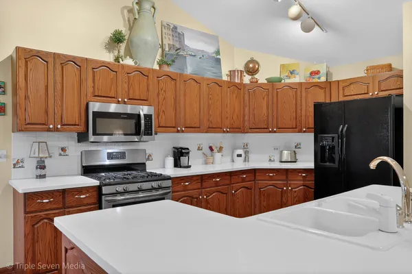 a kitchen with stainless steel appliances a refrigerator stove microwave and sink with wooden cabinets