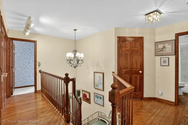 a view of a hallway with a chandelier and wooden floor