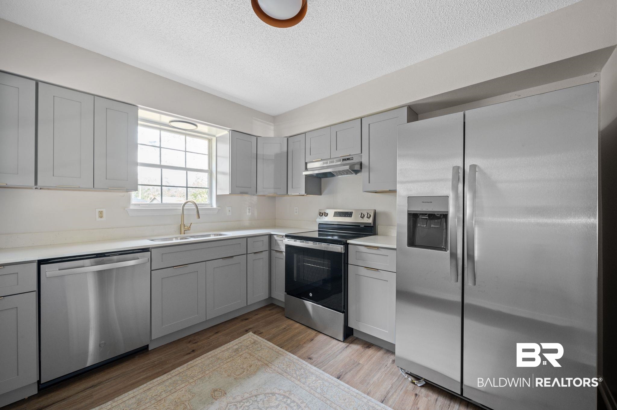 811 East Verbena Avenue Foley, AL 36535 - Photo 12 of 16 Kitchen with appliances with stainless steel finishes, light hardwood / wood-style floors, gray cabinets, and sink