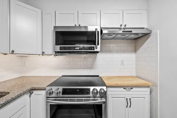 a kitchen with stainless steel appliances granite countertop a sink and a white cabinets