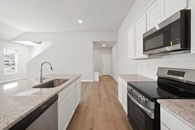 a kitchen with granite countertop a sink and stainless steel appliances