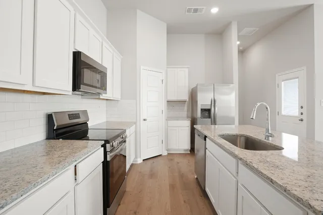 a kitchen with granite countertop a sink dishwasher stove and refrigerator with wooden floor