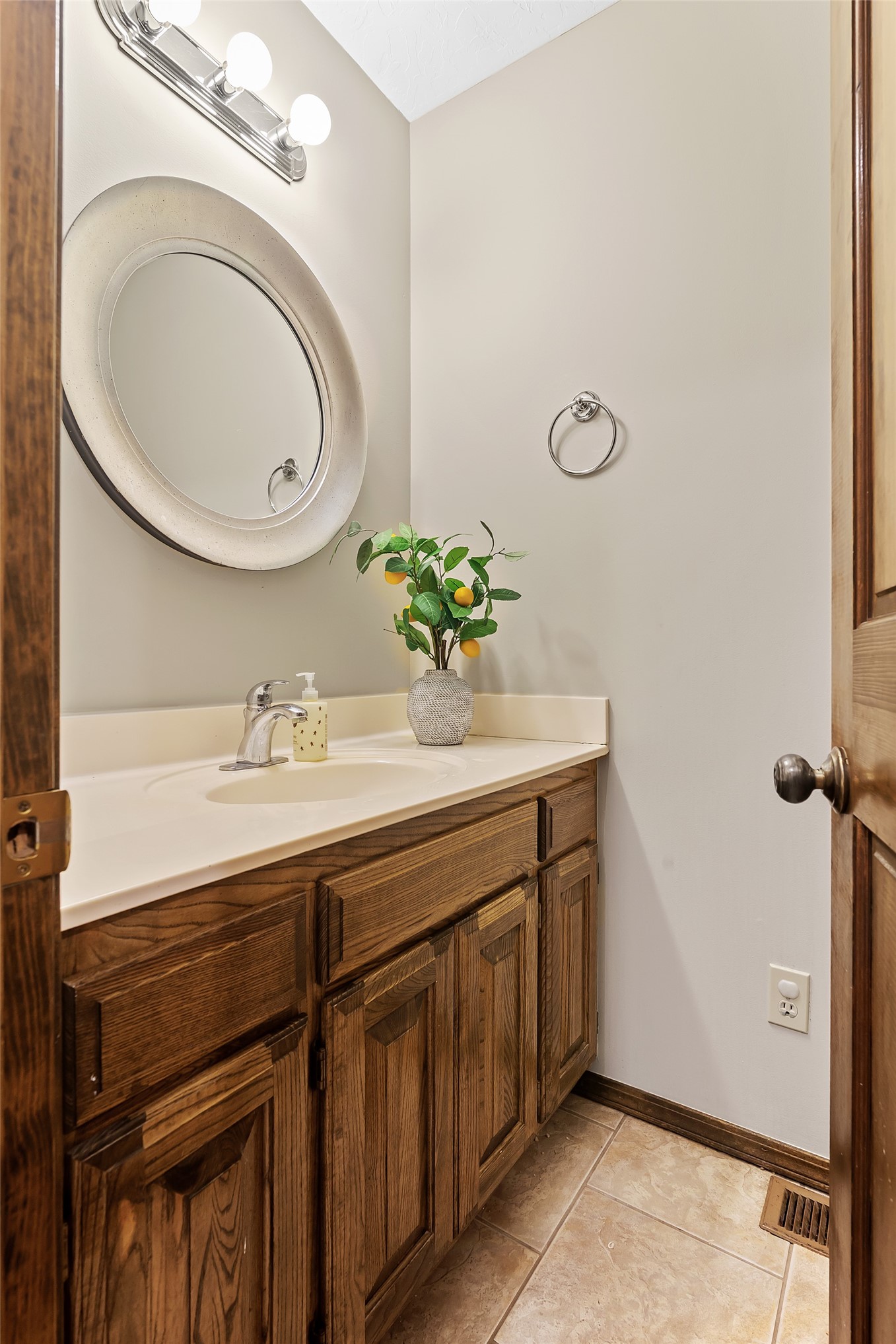 9644 19th Road Nowata, OK 74048 - Photo 18 of 36 Bathroom vanity featuring wood cabinetry, a light-toned countertop, and an undermount sink with a chrome faucet