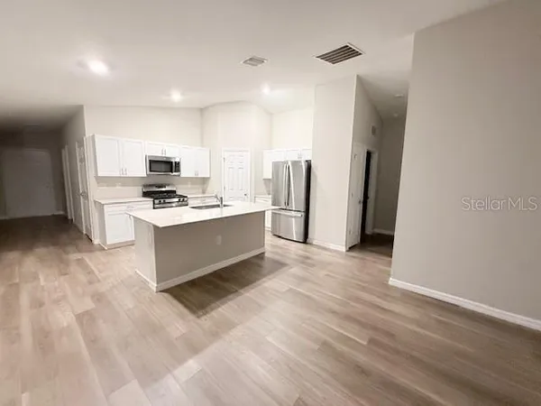 a large kitchen with stainless steel appliances a refrigerator and a stove top oven