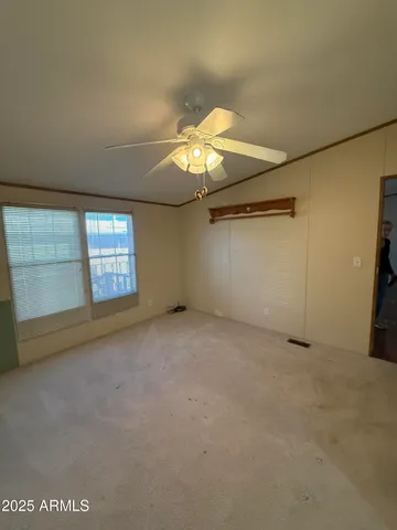 an empty room with windows and chandelier fan