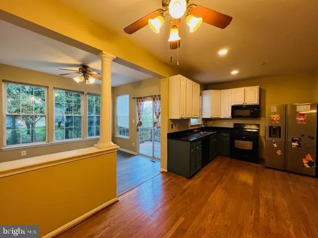 a large kitchen with stainless steel appliances granite countertop a refrigerator a oven a dining table and chairs with wooden floor