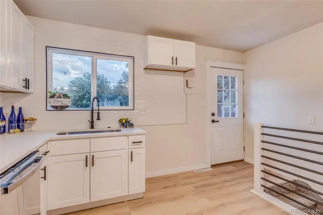 a kitchen with white cabinets and sink