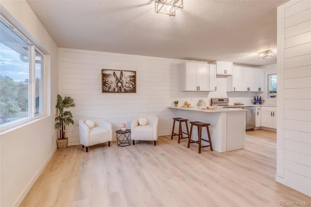 a living room with stainless steel appliances kitchen island granite countertop furniture and a wooden floor