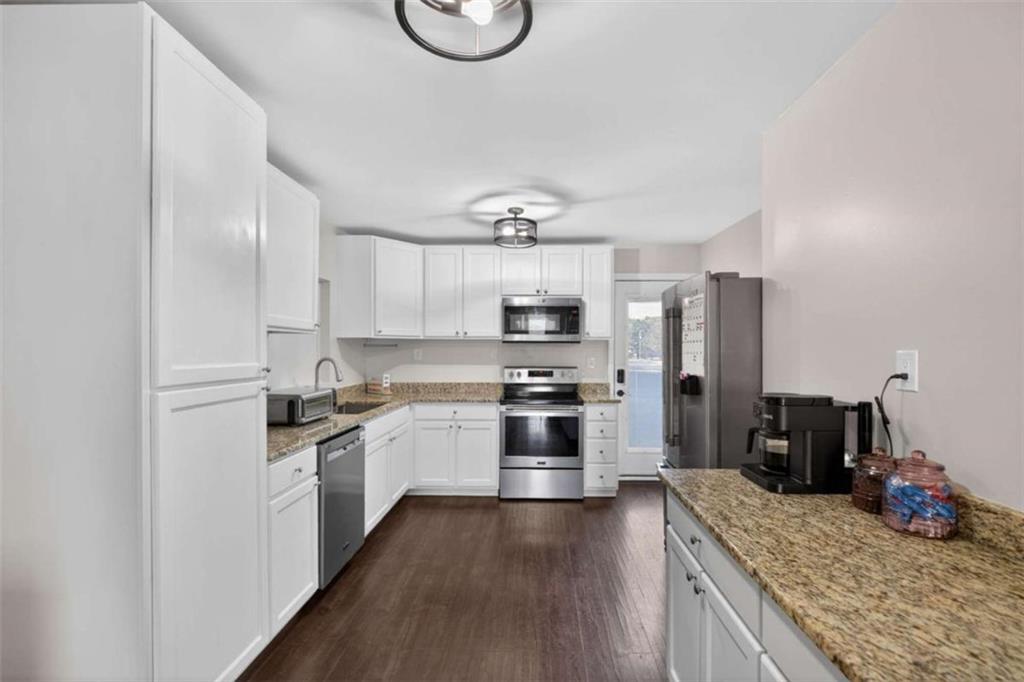 507 Grogan Road Buchanan, GA 30113 - Photo 11 of 31 a kitchen with stainless steel appliances granite countertop a stove top oven a refrigerator a sink and dishwasher with wooden floor