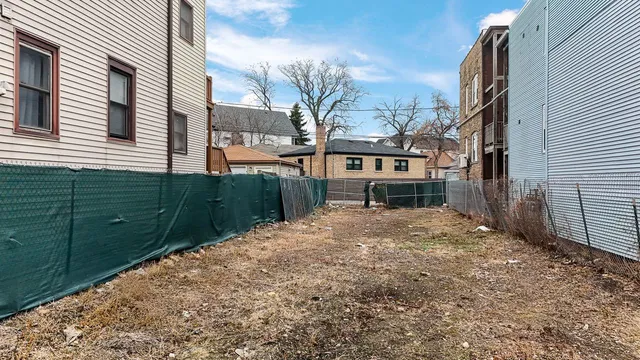 a view of a house with a small yard and wooden fence