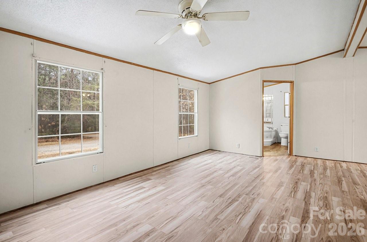 40348 Barnhardt Road New London, NC 28127 - Photo 19 of 38 an empty room with wooden floor chandelier fan and windows
