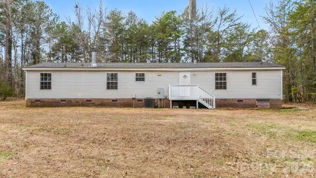 a view of a house with backyard and trees in the background