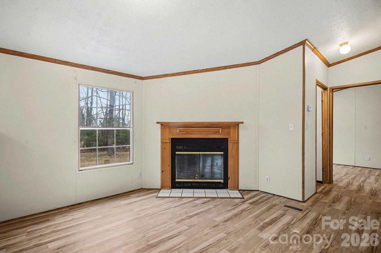 40348 Barnhardt Road New London, NC 28127 - Photo 9 of 38 a view of an empty room with wooden floor fireplace and a window