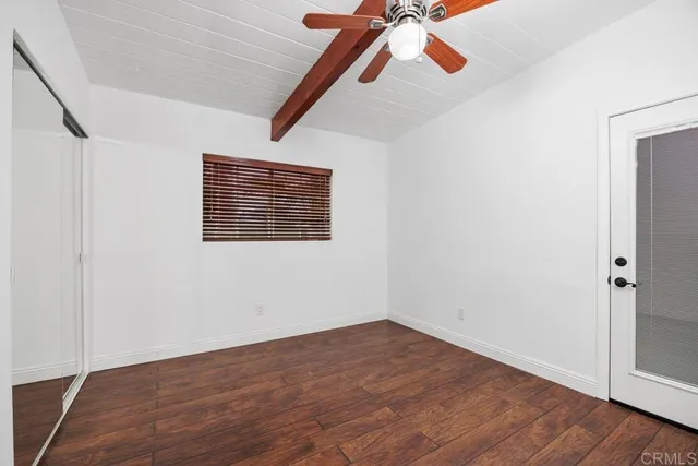 a view of an empty room with wooden floor and a ceiling fan