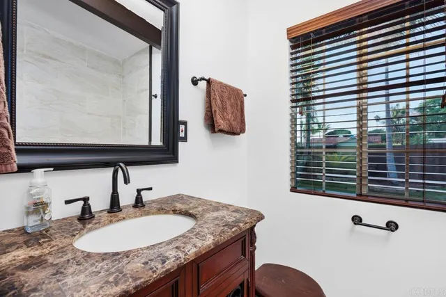 a bathroom with a granite countertop sink and a mirror