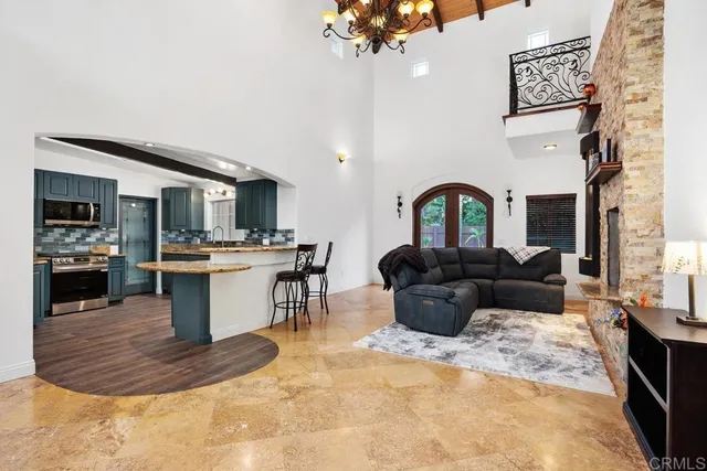 a living room with furniture a chandelier and kitchen view